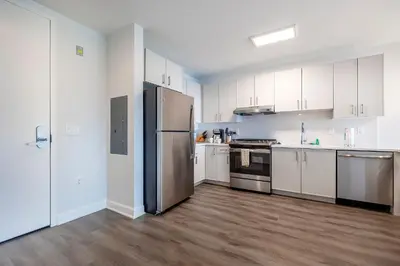 a kitchen with white cabinets and a stainless steel refrigerator at Private Luxury Apt with Gym in Stamford
