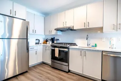 a kitchen with white cabinets and a stainless steel refrigerator at Private Luxury Apt with Gym in Stamford