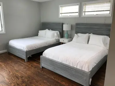two beds in a bedroom with white walls and wood floors at Luxury Woodstock Family Retreat with pool hot tub in Woodstock