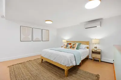 a white bedroom with a bed and a night stand at Vintage Luxe NY - Designer Lofts & Apartments NYC in New York