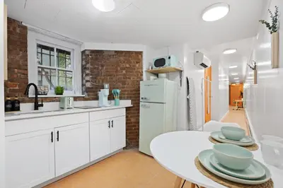 a kitchen with white cabinets and a white refrigerator at Vintage Luxe NY - Designer Lofts & Apartments NYC in New York