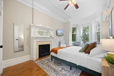 a white bedroom with a bed and a fireplace at Vintage Luxe NY - Designer Lofts & Apartments NYC in New York