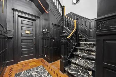 a black hallway with a staircase with black walls and wood paneling at Vintage Luxe NY - Designer Lofts & Apartments NYC in New York