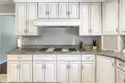 a kitchen with white cabinets and a stove top oven at Akasa in Stratford