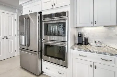 a kitchen with stainless steel appliances and white cabinets at Sunrise Waterfront Retreat in Milford