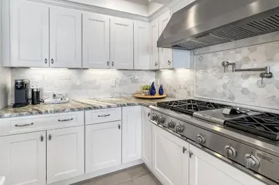 a kitchen with white cabinets and a stove at Sunrise Waterfront Retreat in Milford
