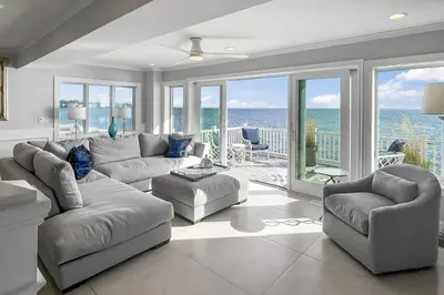 a living room with a couch and chairs and the ocean at Sunrise Waterfront Retreat in Milford