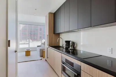a kitchen with black counter tops and wooden cabinets at Blueground Midtown West gym doorman wd NYC-1560 in New York