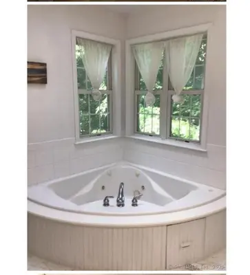 a large tub in a bathroom with two windows at Enjoy all Westport has to offer! in Westport