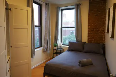 a bedroom with a bed and two windows at Family Friendly 4BR 2BA in Prime NYC Location in New York