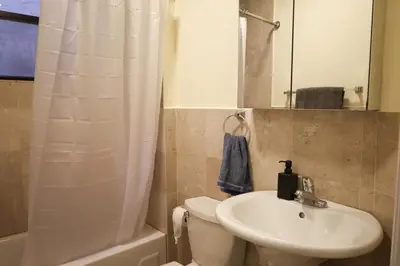 a bathroom with a sink and a toilet and a mirror at Family Friendly 4BR 2BA in Prime NYC Location in New York