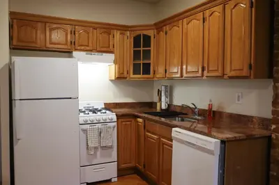 a kitchen with a white refrigerator and wooden cabinets at Family Friendly 4BR 2BA in Prime NYC Location in New York
