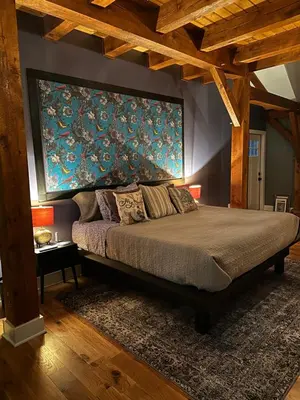 a bedroom with a bed with a large painting on the wall at BataviaKill Homestead in Prattsville