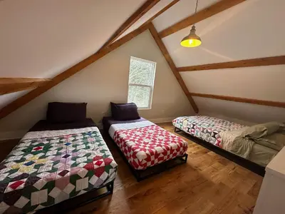 a attic room with two beds and a window at BataviaKill Homestead in Prattsville