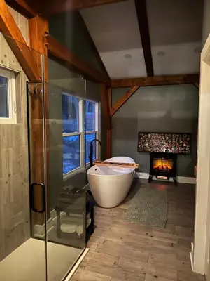 a bathroom with a bath tub and a fireplace at BataviaKill Homestead in Prattsville
