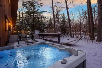 a jacuzzi tub in the snow in a yard at Private Hot Tub and Game Room Pocono Family Cabin! in Tobyhanna