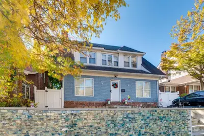 a blue house with a stone fence in front of it at 1 Mi to Train Station Quiet Apartment in Newark in Newark