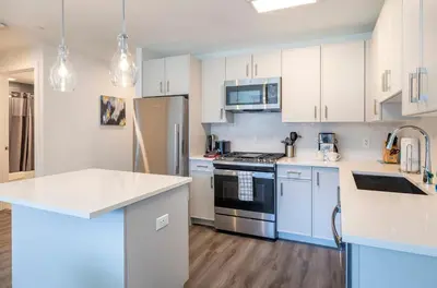 a kitchen with white cabinets and blue appliances at Modern Apt Close to Downtown in Stamford