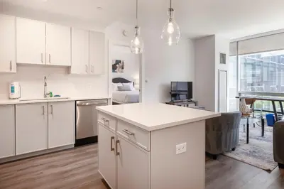 a kitchen with white cabinets and a living room at Modern Apt Close to Downtown in Stamford