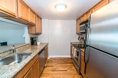a kitchen with a stainless steel refrigerator and wooden cabinets at Private Apt Close to Train in Stamford
