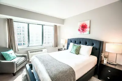 a bedroom with a bed and a chair and a window at Entire Apt Downtown with Gym in Stamford