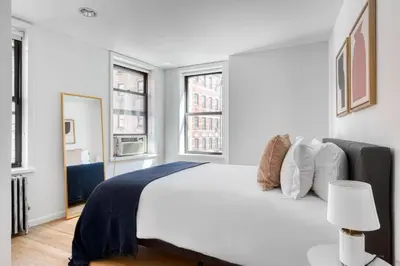 a white bedroom with a large bed and two windows at Nolita 2br w wd nr SoHo NYC-955 in New York