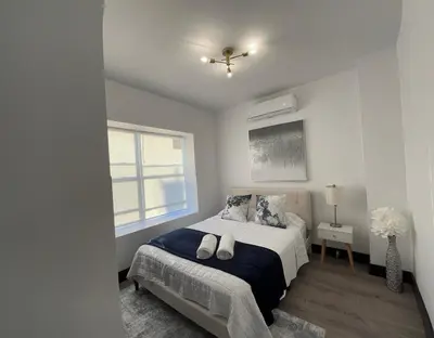 a white bedroom with a bed and a window at Apartment Few Minutes NYC and Prudential Center in Newark