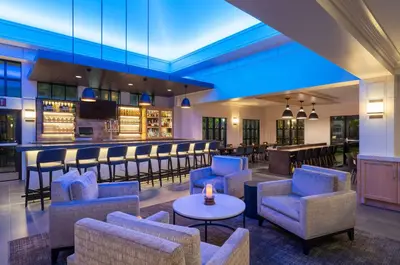 a lobby with chairs and a bar in the background at Hyatt House White Plains in White Plains