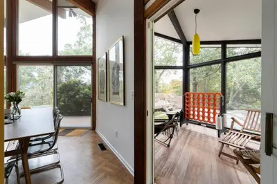 a living room with a table and chairs and windows at Quarry House Mid-Century Modern in Haddam