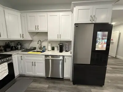 a kitchen with white cabinets and a black refrigerator at The Luxury Suite - 1BR with Gym & Office in Paterson
