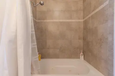 a bath tub with a shower curtain in a bathroom at King Master and Plush Queen near NYC w kitchen, living room plus on-site gym in Jersey City