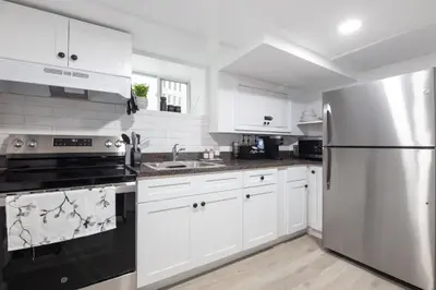 a kitchen with white cabinets and a stainless steel refrigerator at Pelham Haven Suite in New York in Pelham