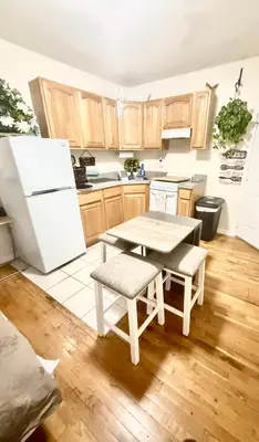 a kitchen with a table and a white refrigerator at Apart Studio West NYNJ 12Mints From NYCity TimeSquare in West New York