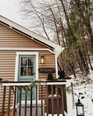 a small house with a porch in the snow at The Little Lake Cabin in New Fairfield