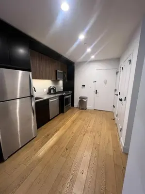 a kitchen with a stainless steel refrigerator and wooden floors at Beautiful 1 Bedroom Condo in Mott Haven