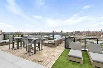 an outdoor patio with tables and chairs on a roof at Beautiful 1 Bedroom Condo in Mott Haven
