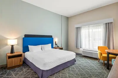a hotel room with a bed and a table and chairs at Hampton Inn Cooperstown in Cooperstown