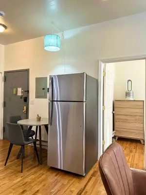 a kitchen with a stainless steel refrigerator and a table at Cottage 215 Apartments in New York