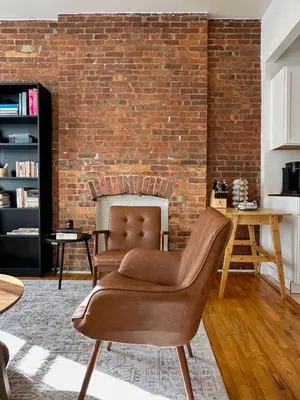 a living room with two chairs and a brick wall at Cottage 215 Apartments in New York