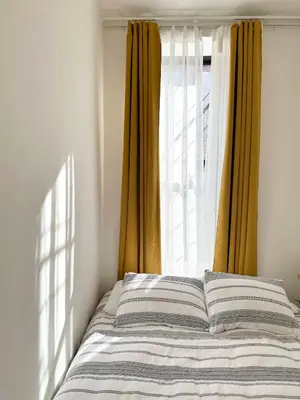 a bed in front of a window with yellow curtains at Cottage 215 Apartments in New York