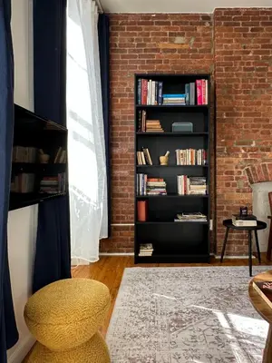 a room with a brick wall and a book shelf with books at Cottage 215 Apartments in New York