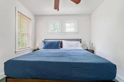 a bedroom with a blue bed with two windows at The Hera Haven - Pickleball, hot tub, racetrack & lake in Stillwater