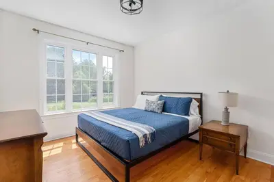 a bedroom with a bed and a desk and windows at The Hera Haven - Pickleball, hot tub, racetrack & lake in Stillwater