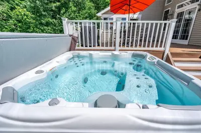 a hot tub on a patio with an umbrella at The Hera Haven - Pickleball, hot tub, racetrack & lake in Stillwater