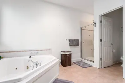 a white bathroom with a tub and a shower at The Hera Haven - Pickleball, hot tub, racetrack & lake in Stillwater