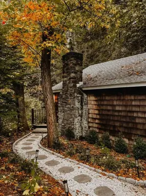 a stone building with a bench next to a tree at Creek Side Cabin with Wood Fired Hot Tub and Fire Pit in New Milford