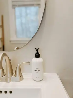 a white bottle of soap sitting on a bathroom sink at Creek Side Cabin with Wood Fired Hot Tub and Fire Pit in New Milford