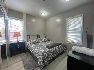 a bedroom with a bed and two windows at Spacious 3 bedroom close to NYC in North Bergen