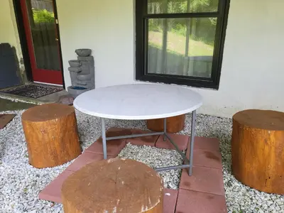 a white table and two logs in front of a house at Serenity Escape in Hudson Valley in Hopewell Junction