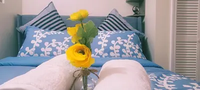 a bed with blue and white pillows and a vase with flowers at Serenity Escape in Hudson Valley in Hopewell Junction